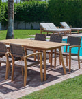 A poolside dining arrangement showcasing a teak dining table surrounded by woven teak chairs, creating a relaxing and stylish outdoor setting.